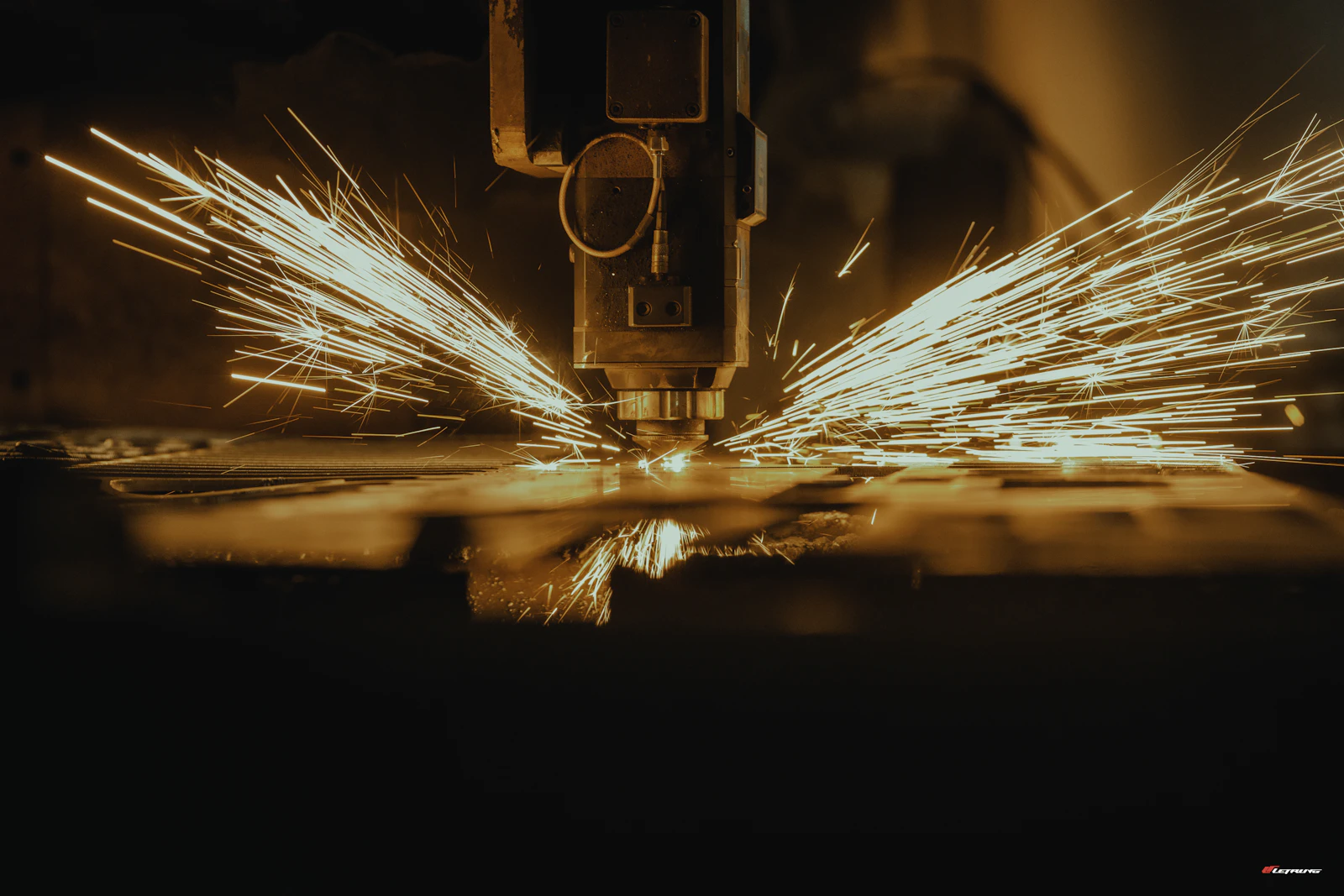 CNC cutting head shaping sheet metal with a spray of sparks